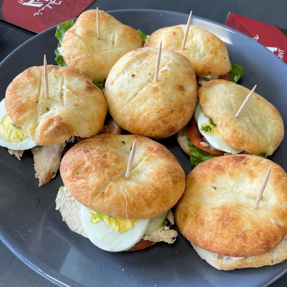 A plate of mini pizza sandwiches with various fillings, including egg, chicken, and vegetables.